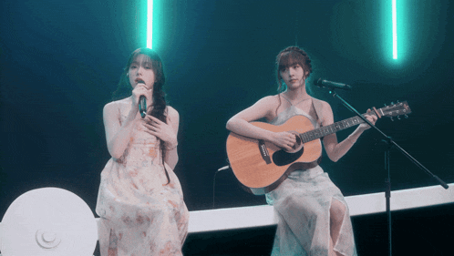 a woman singing while another woman plays guitar