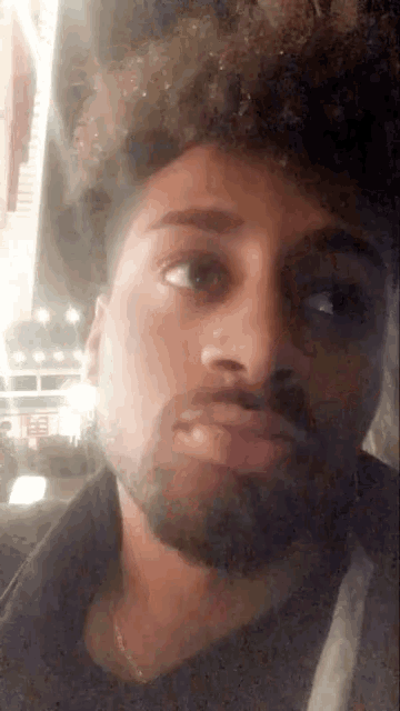 a close up of a man 's face with a beard and curly hair
