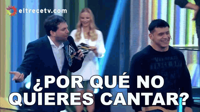 a man in a suit stands in front of a sign that says por que no quieres cantar ?
