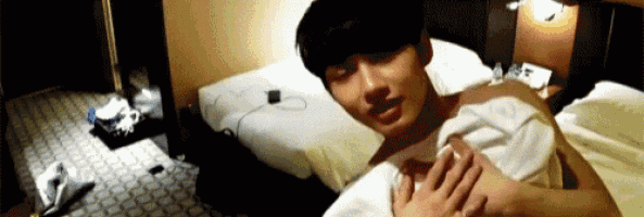 a shirtless man is laying on a bed with a white towel around his shoulders .