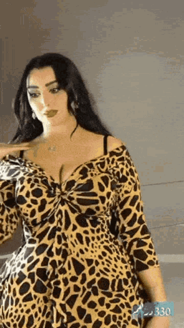 a woman is wearing a leopard print dress and standing in front of a mirror .