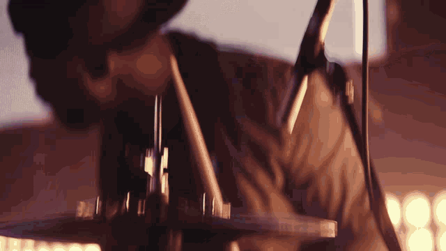 a close up of a person playing drums with a microphone behind them