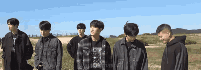 a group of young men are standing in a field with a fence in the background