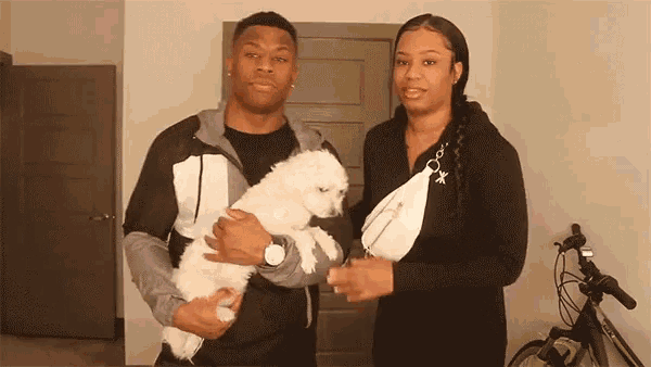 a man and a woman holding a white dog