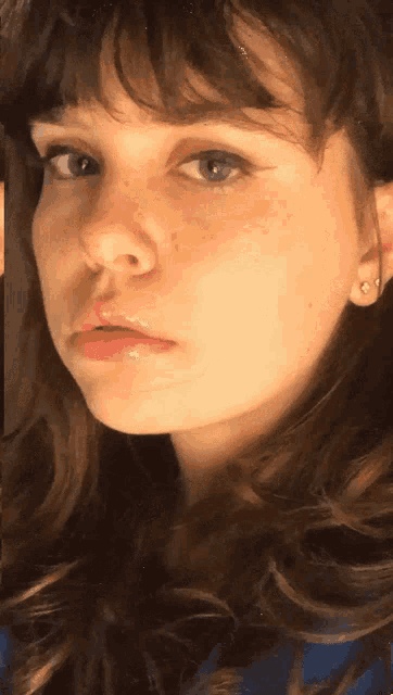 a close up of a young woman 's face with a blue shirt on