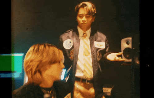 a man in a suit and tie stands next to another man