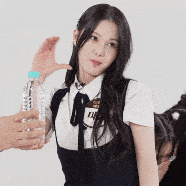a girl with a name tag that says ' i ' on it holds a bottle of water in her hand