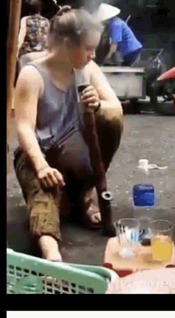 a woman sitting on the ground with a bottle of water in the background