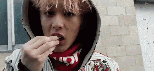 a young man wearing a hoodie and a scarf is eating something .