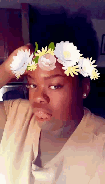 a woman wearing a flower crown on her head looks at the camera