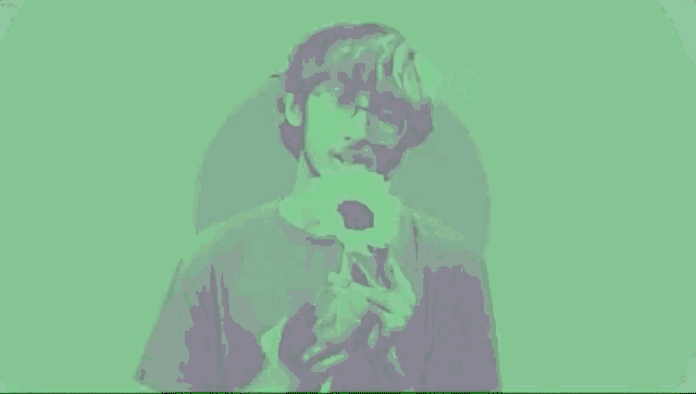 a man with a beard and glasses is holding a flower in his mouth .