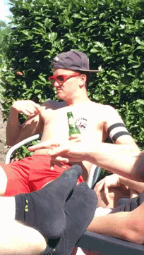 a shirtless man with a bottle of beer in his pocket is laying on a chair