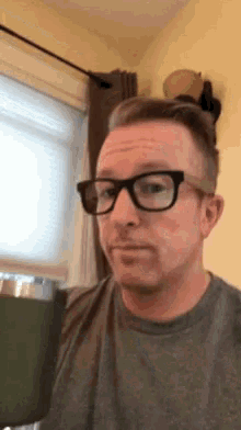 a man wearing glasses and a grey shirt is making a face
