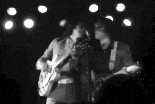 a man is playing a guitar and singing into a microphone on stage .