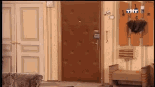 a tv screen shows a hallway with a brown door and a umbrella hanging on a rack ..