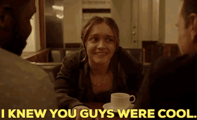 a woman is sitting at a table with a cup of coffee and a man says i knew you guys were cool .