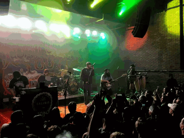 a group of people are standing in front of a stage with a sign that says ' a few dollars '