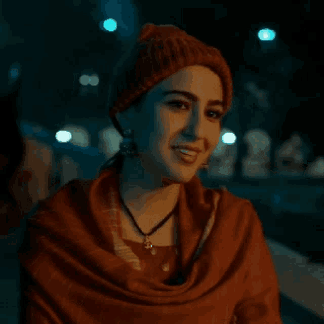 a woman wearing a red scarf and a beanie is smiling
