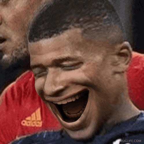 a man wearing an adidas shirt is laughing with his mouth wide open