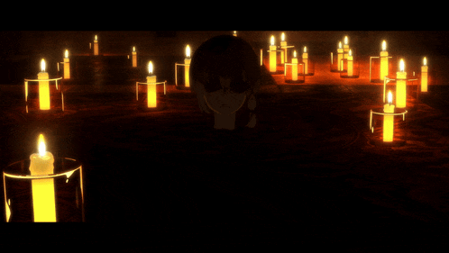 a person kneeling in front of a bunch of candles