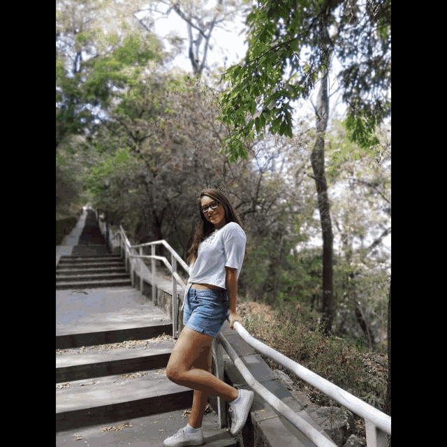 a girl standing on a set of stairs with trees behind her