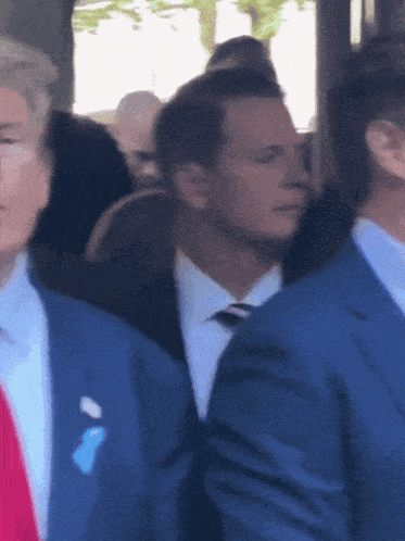a man in a suit with a blue button on his pocket