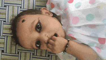 a baby wearing a polka dot dress is laying on a blanket