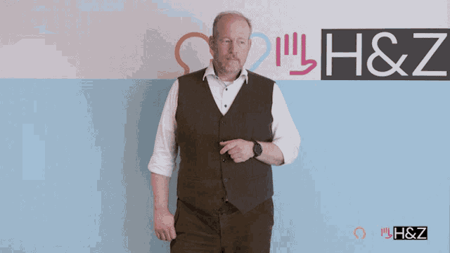a man pointing in front of a wall that has the letters h & z on it