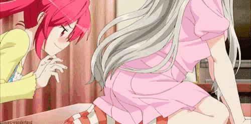 a couple of anime girls are sitting on a bed and one of them is looking at the other 's butt .