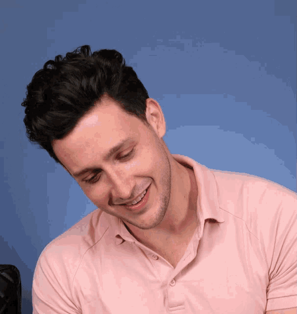 a man wearing a pink polo shirt with the letter r on the front