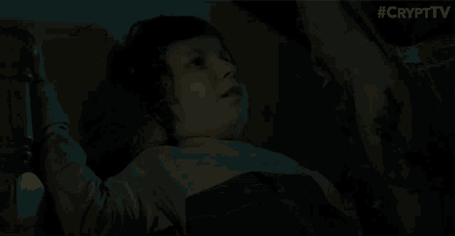 a young boy is laying in bed in the dark and taking a selfie with his phone .