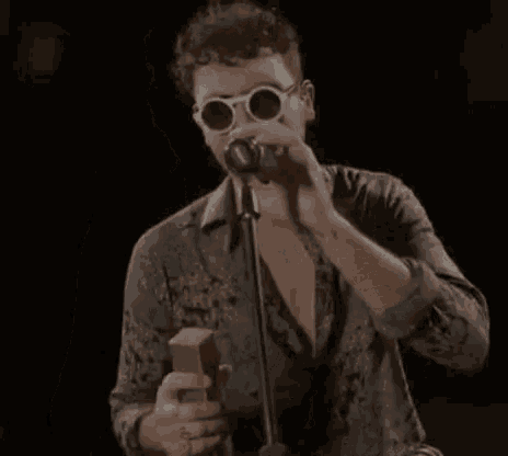 a man singing into a microphone with the word chapeau on the bottom right