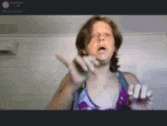 a woman is making a funny face while holding a white object in her hand .