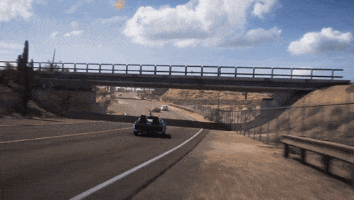 a car is driving under a bridge on a desert road