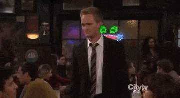a man in a suit and tie is standing in front of a crowd in a bar .
