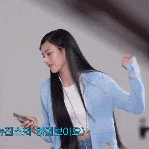 a woman with long black hair is wearing headphones and holding a cell phone