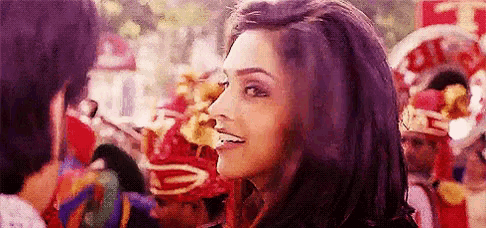 a woman is smiling at a man in front of a crowd of people .
