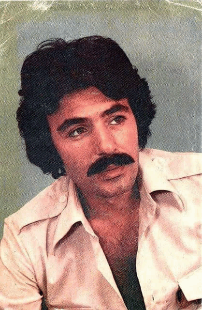a man with long hair and a mustache is wearing a white shirt .
