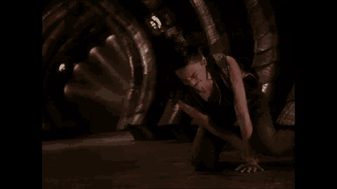 a woman is kneeling on the floor in a dark room