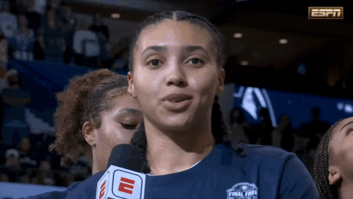 a woman wearing a blue shirt that says espn on it talks into a microphone