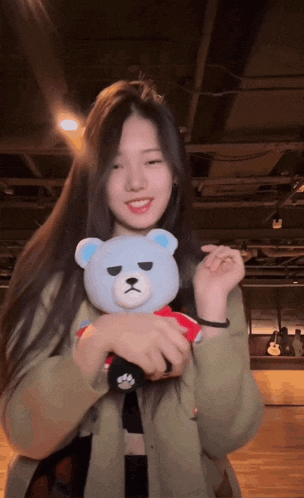 a girl is holding a stuffed teddy bear in her hands