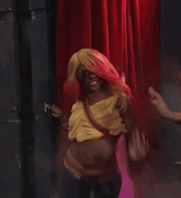 a woman wearing a yellow top and blue jeans is dancing on a street .