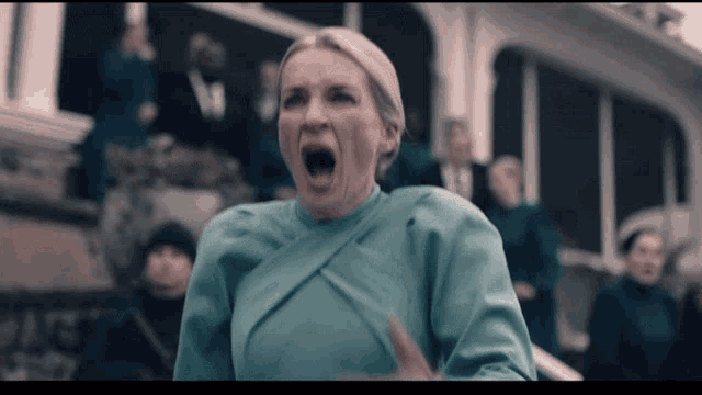a woman in a blue dress screams in front of a group of people