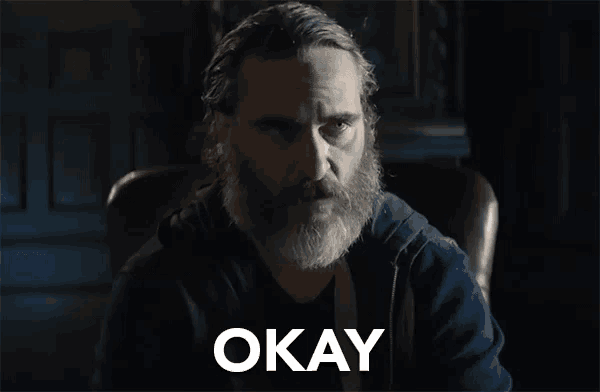a man with a beard is sitting in a chair with the word okay in front of him