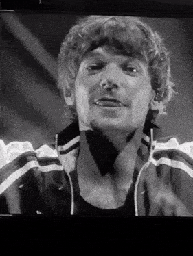 a black and white photo of a man with curly hair and a striped jacket
