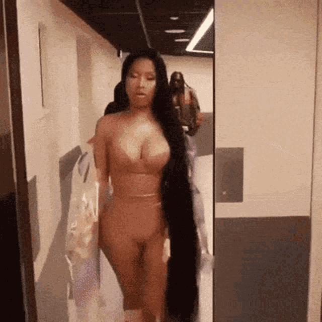 a woman with long hair is walking down a hallway .