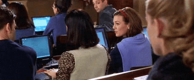 a group of people are sitting in front of laptops in a lecture hall .