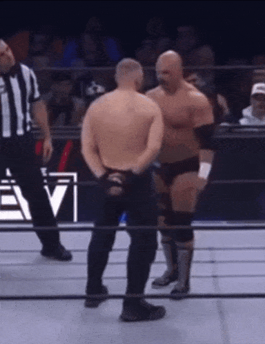 two wrestlers are standing in a ring with a referee and a sign that says evi on it