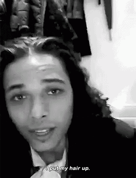 a black and white photo of a man with long hair wearing a suit and tie and saying `` i put my hair up . ''