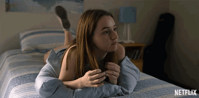a woman is laying on a bed with a netflix logo on the bottom